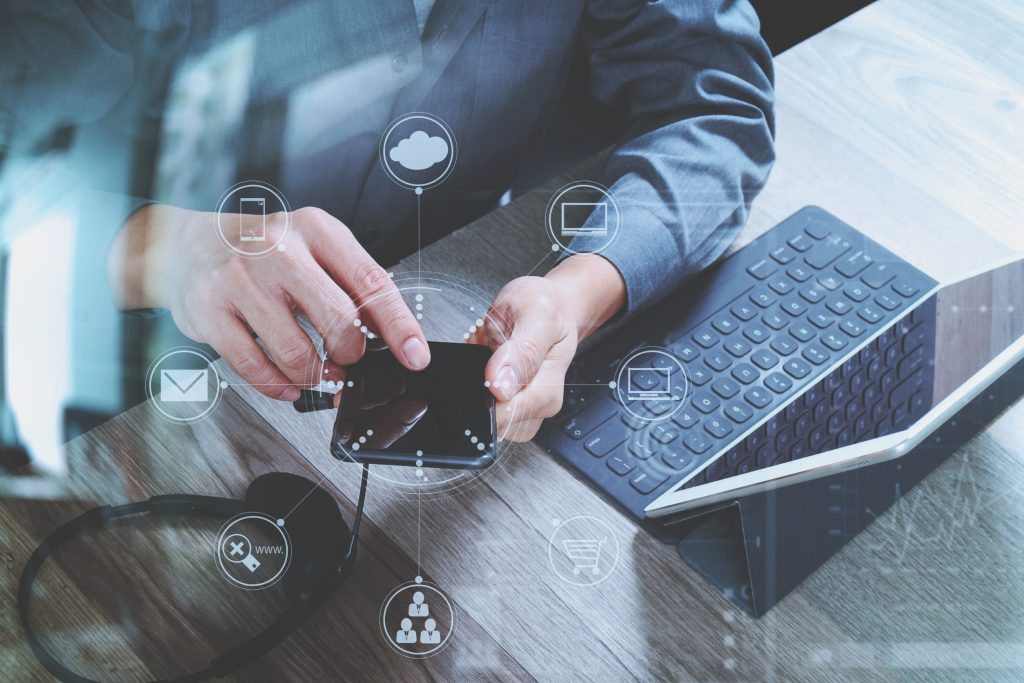 top view of man hand using VOIP headset with digital tablet computer docking keyboard,smart phone,concept communication, it support, call center and customer service help desk on wooden table,virtual interface icons screen