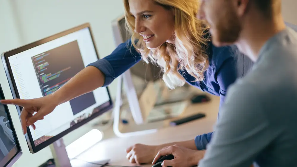 Man and woman discussing project at a computer station