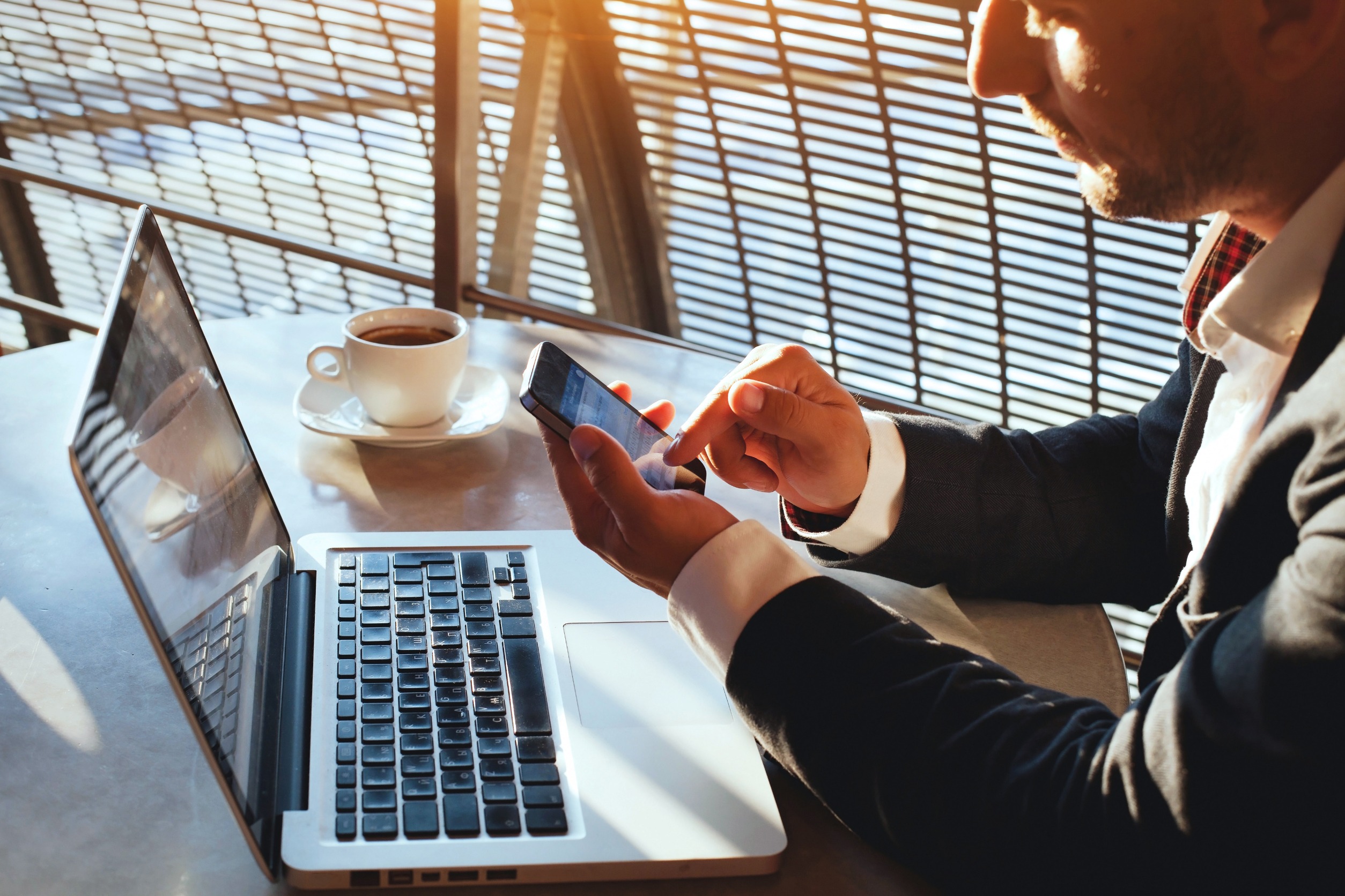 A man working at a table with his laptop and smart phone