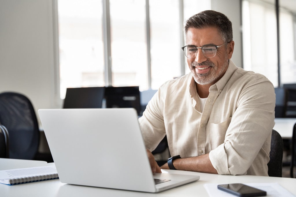 MSP Corp image showing a professional working on a laptop in a modern office, illustrating Microsoft 365 managed services and operational oversight